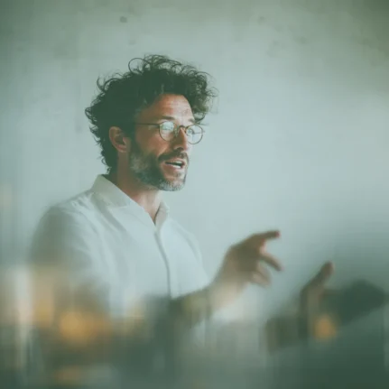 Tutor delivering a lesson, with animated expression and pointing.